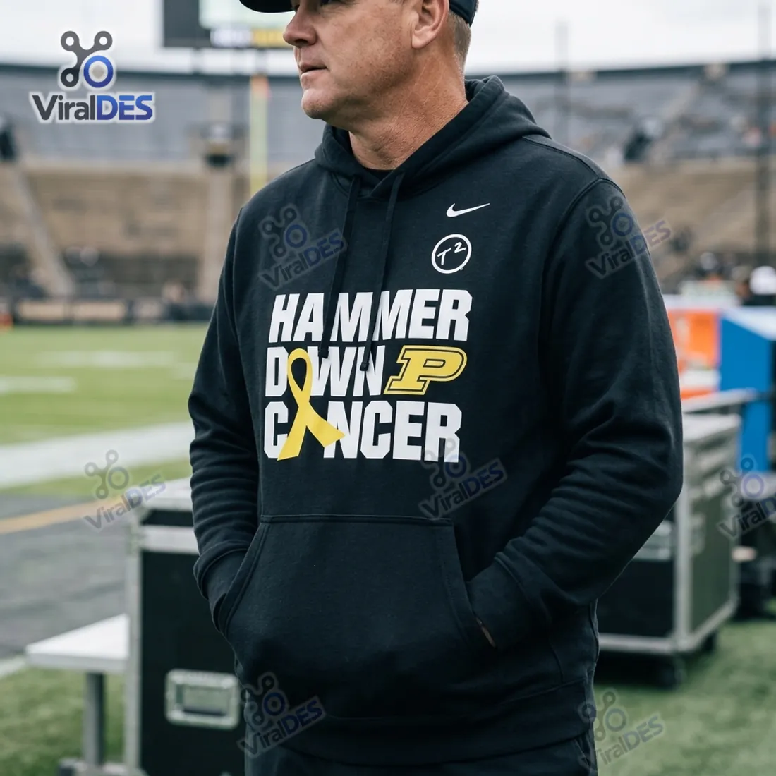 Purdue Boilermakers Hammer Down Cancer Black Hoodie worn on the football sideline showing T2 badge and gold ribbon chest graphic