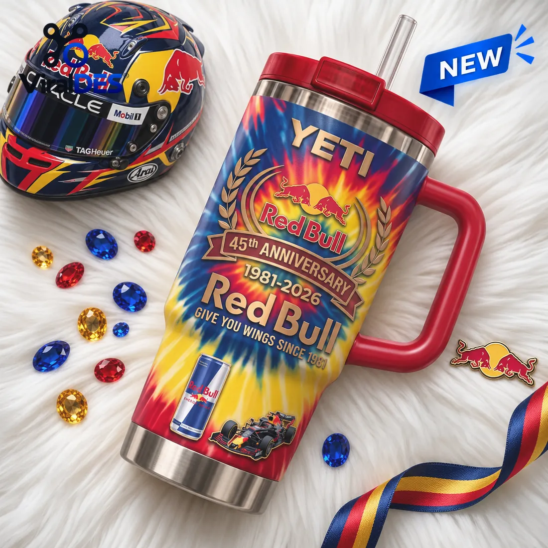 Flat-lay collector view of the Red Bull 45th Anniversary YETI Handle Tumbler beside a racing helmet and twin-bull emblem pin