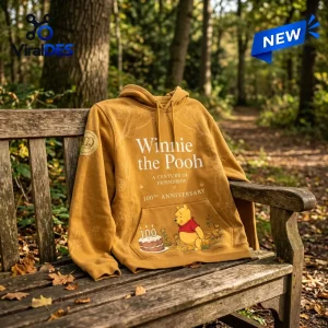 Front view of the Winnie the Pooh 100th Anniversary Yellow Hoodie placed on a wooden park bench.