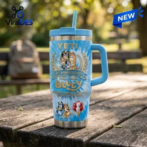 Front view of a Bluey 8th Anniversary Blue Stanley Tumbler 40oz resting on a wooden picnic table outdoors.