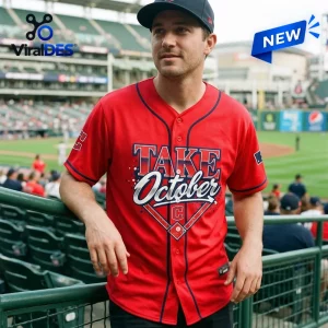 Man wearing red baseball jersey with Take October text in stadium seats.