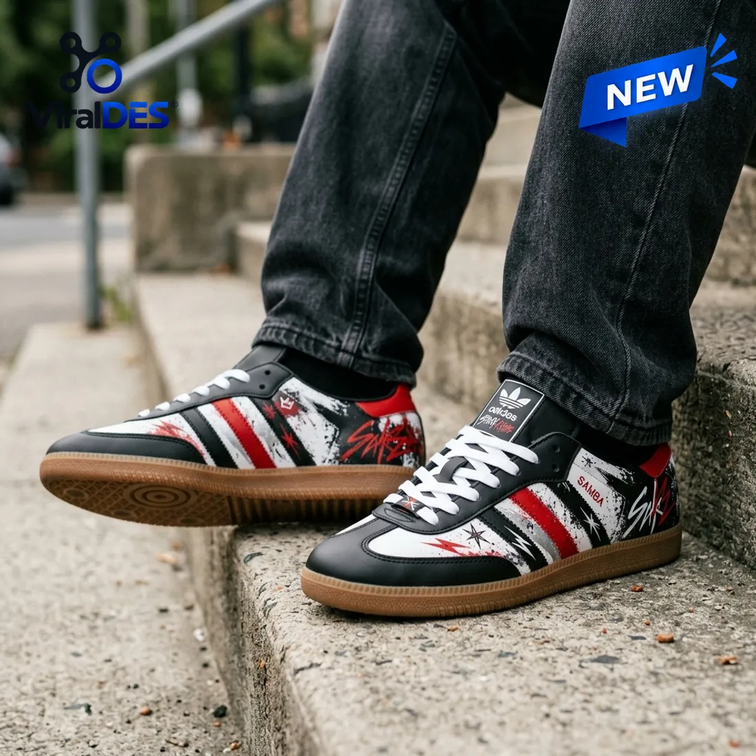 Low angle view of Stray Kids Black Red Samba Sneakers worn with dark jeans on outdoor stone steps.