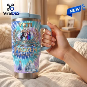 Hand holding a Frozen 13th Anniversary Stanley Tumbler with character graphics.