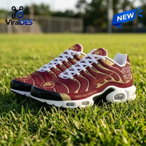 Side view of Brisbane Lions 2026 AFL Premiers Air Max Plus sneakers resting on green grass.