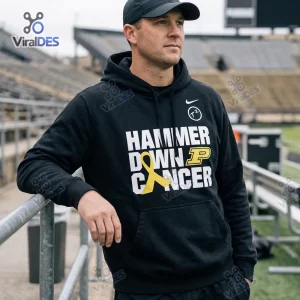 Man wearing the Purdue Boilermakers Hammer Down Cancer black hoodie while leaning against stadium railing.