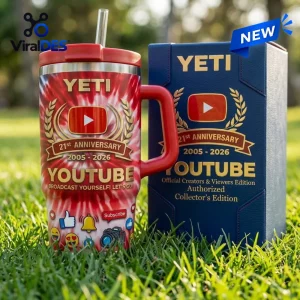 Front view of a red YouTube 21st Anniversary Stanley Handle Tumbler standing in grass next to its matching box.